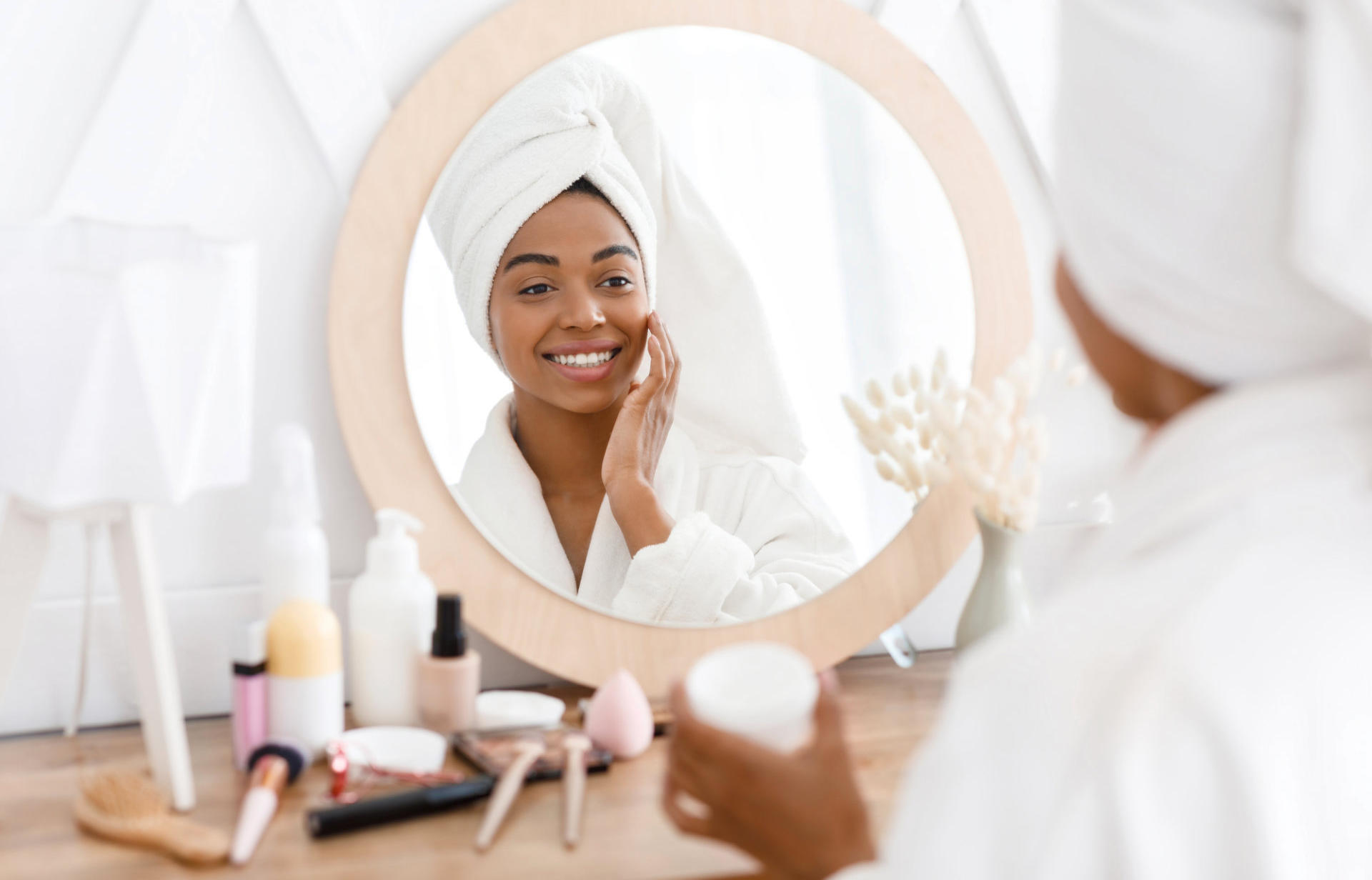 Woman smiling in mirror with Skincare Products